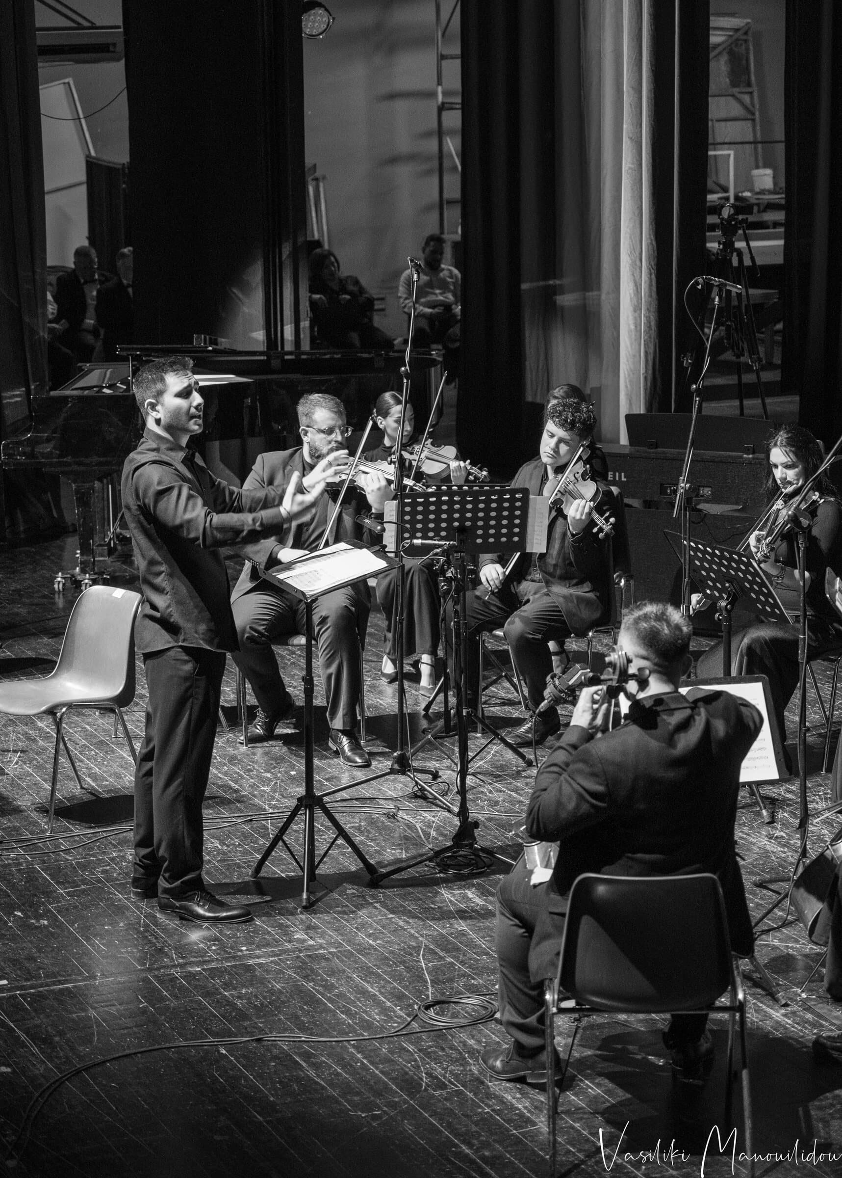 Vaggelis Stavropoulos conducting a chamber orchestra, black and white