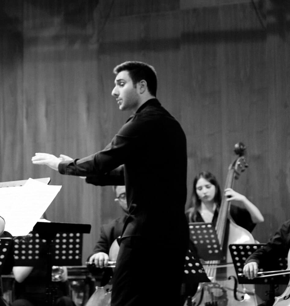 Vaggelis Stavropoulos conducting an orchestra, black and white